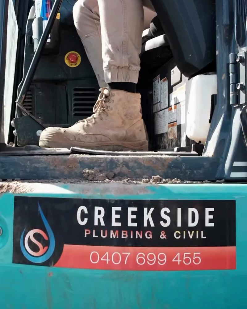 A Creekside Plumbing & Civil decal on the excavator, with the phone number